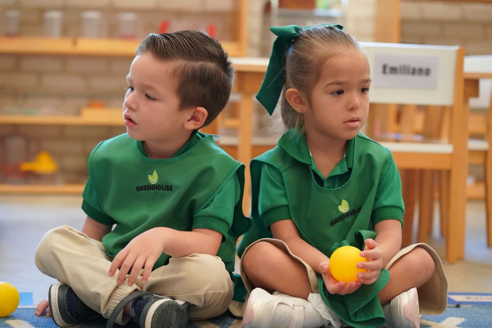 Niños de Pre-K sentados en círculo con pelotas durante una actividad grupal en Greenhouse