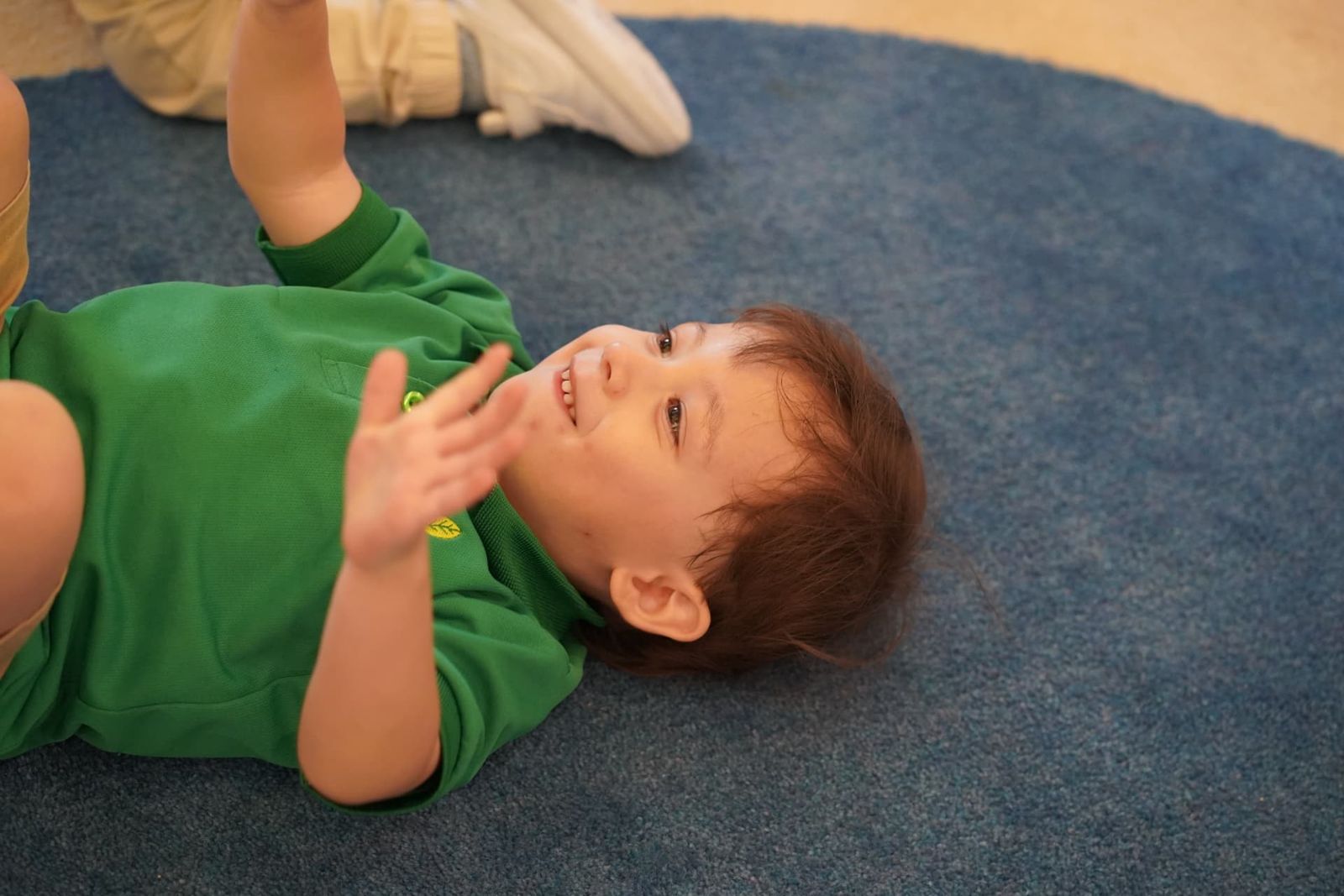 Niño jugando y riendo en el piso durante una clase en Greenhouse