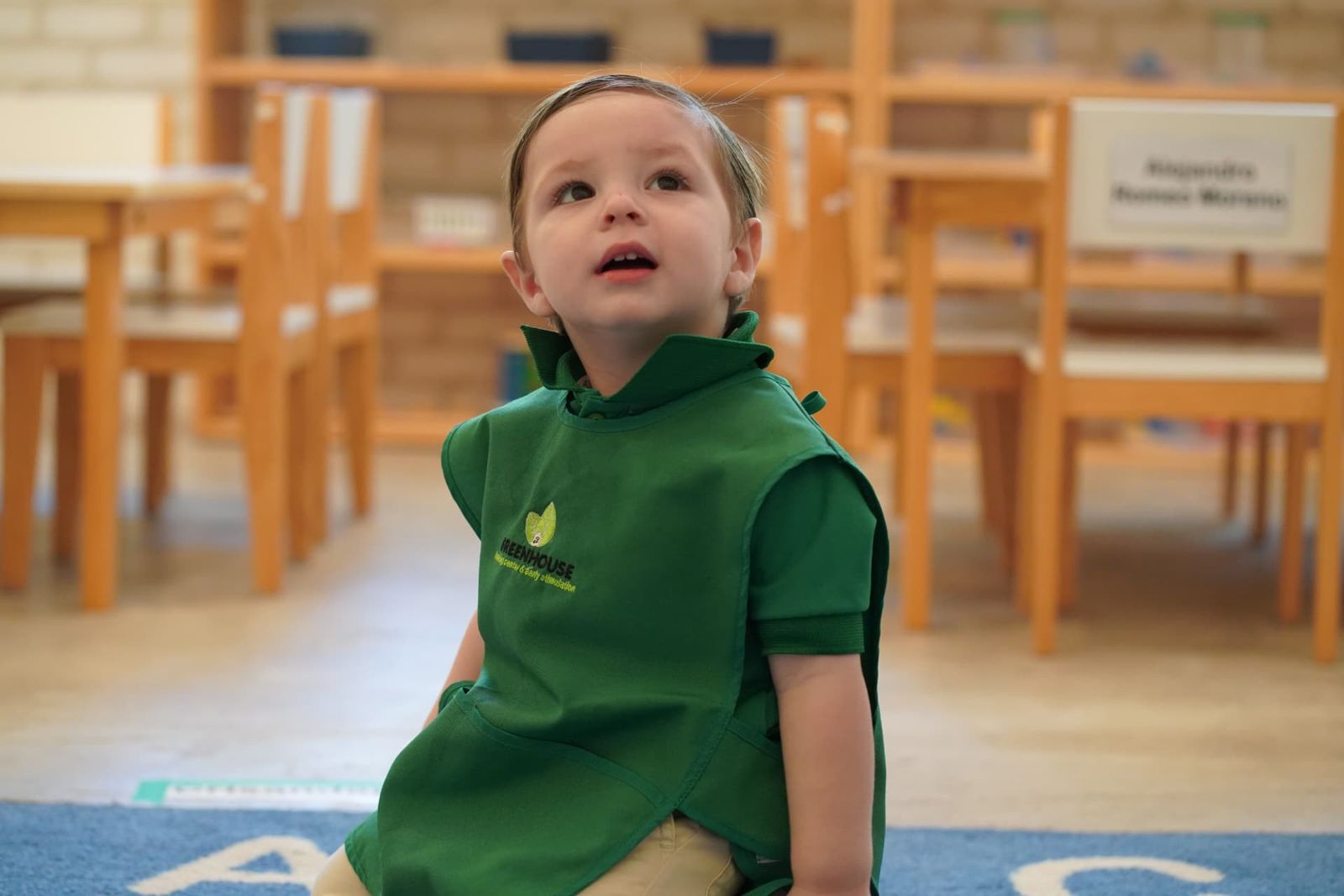 Niño con mandil verde de Greenhouse en el salón con material de madera